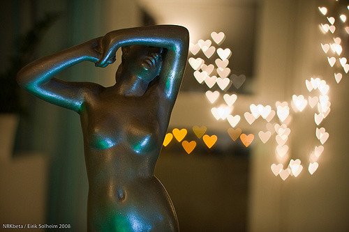 A figurine of a womans body in front of bokeh lights.